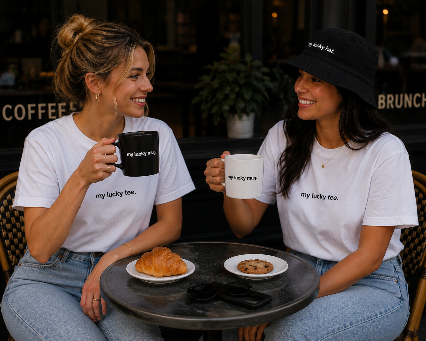 Two women in MY LUCKY tees and hat at a café